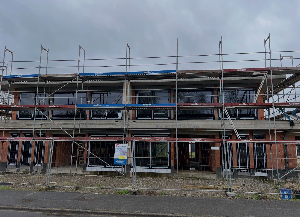 Reihenhauszeile im Bau mit Gerüst und neuen Fenstern